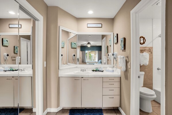 A modern bathroom with two sinks, a large mirror, and a shower.
