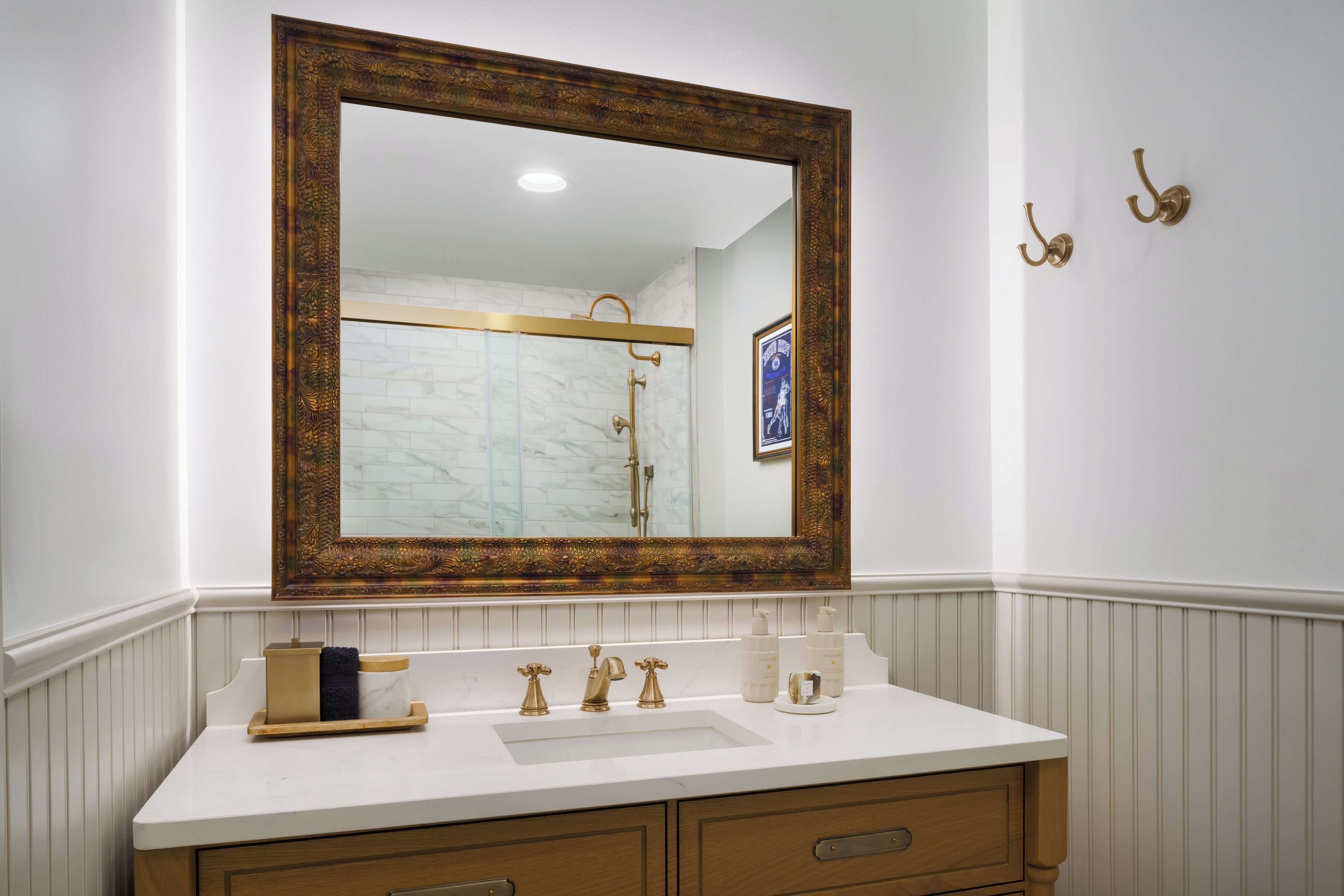 A bathroom with a large mirror, a white sink, and gold fixtures.
