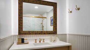 A bathroom with a large mirror, a white sink, and gold fixtures.