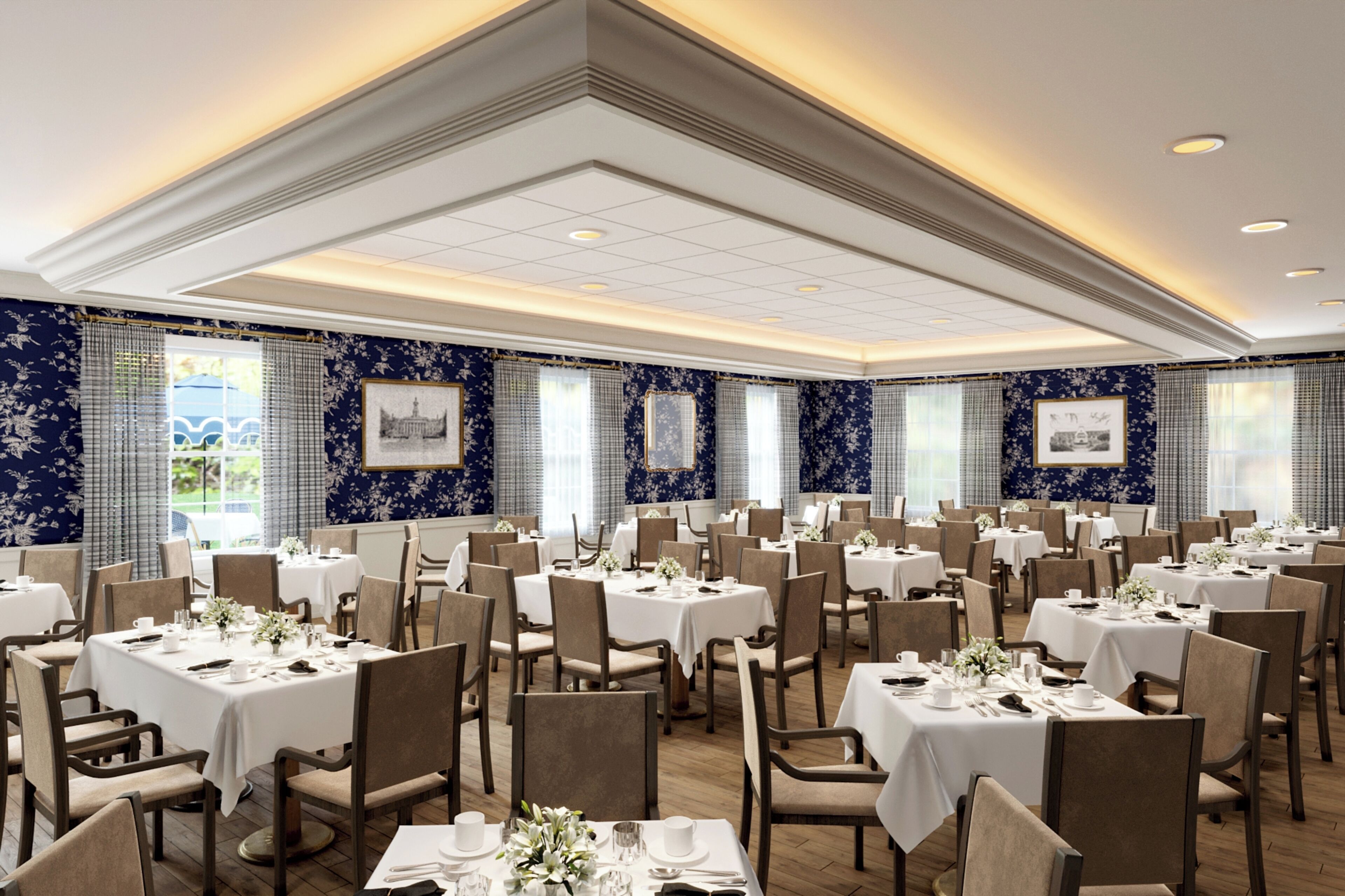 A large banquet hall with multiple tables set for dining, featuring a classic design with white tablecloths and floral centerpieces.