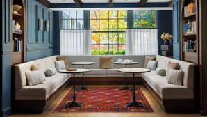 A room with a large window, a sofa, two small tables, and a patterned rug.
