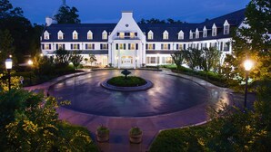 A large, white, multi-story building with a symmetrical facade, a central entrance, and a circular driveway.