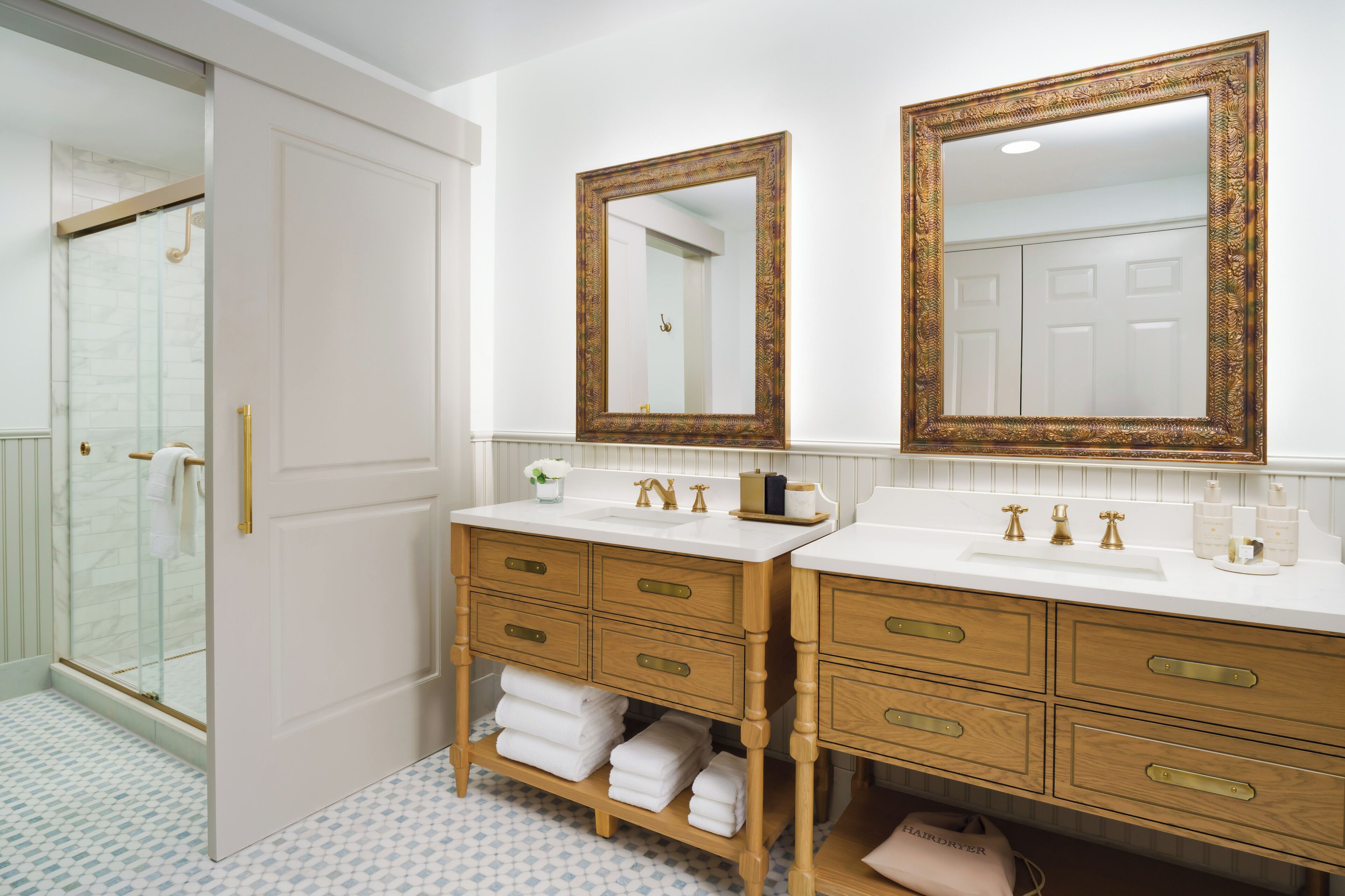 A bathroom with two sinks, wooden vanity, and a large mirror.