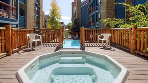 A hot tub on a wooden deck with a view of buildings in the background. - River Mountain Lodge (Breckenridge)