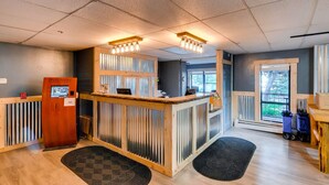 A reception area with a wooden counter, a DVD player, and a window with a view of greenery. - River Mountain Lodge (Breckenridge)