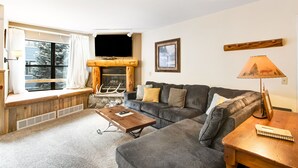 A cozy living room with a fireplace, a sofa, a coffee table, and a lamp. - River Mountain Lodge (Breckenridge)