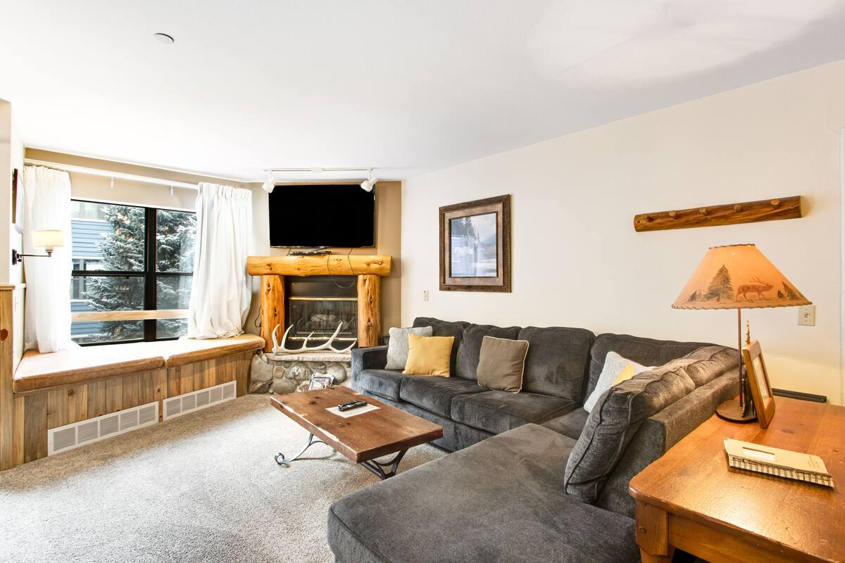 A cozy living room with a fireplace, a sofa, a coffee table, and a lamp.