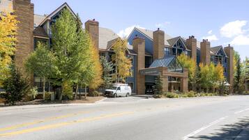 A hotel with a brick facade, multiple chimneys, and a parking lot with a white van.