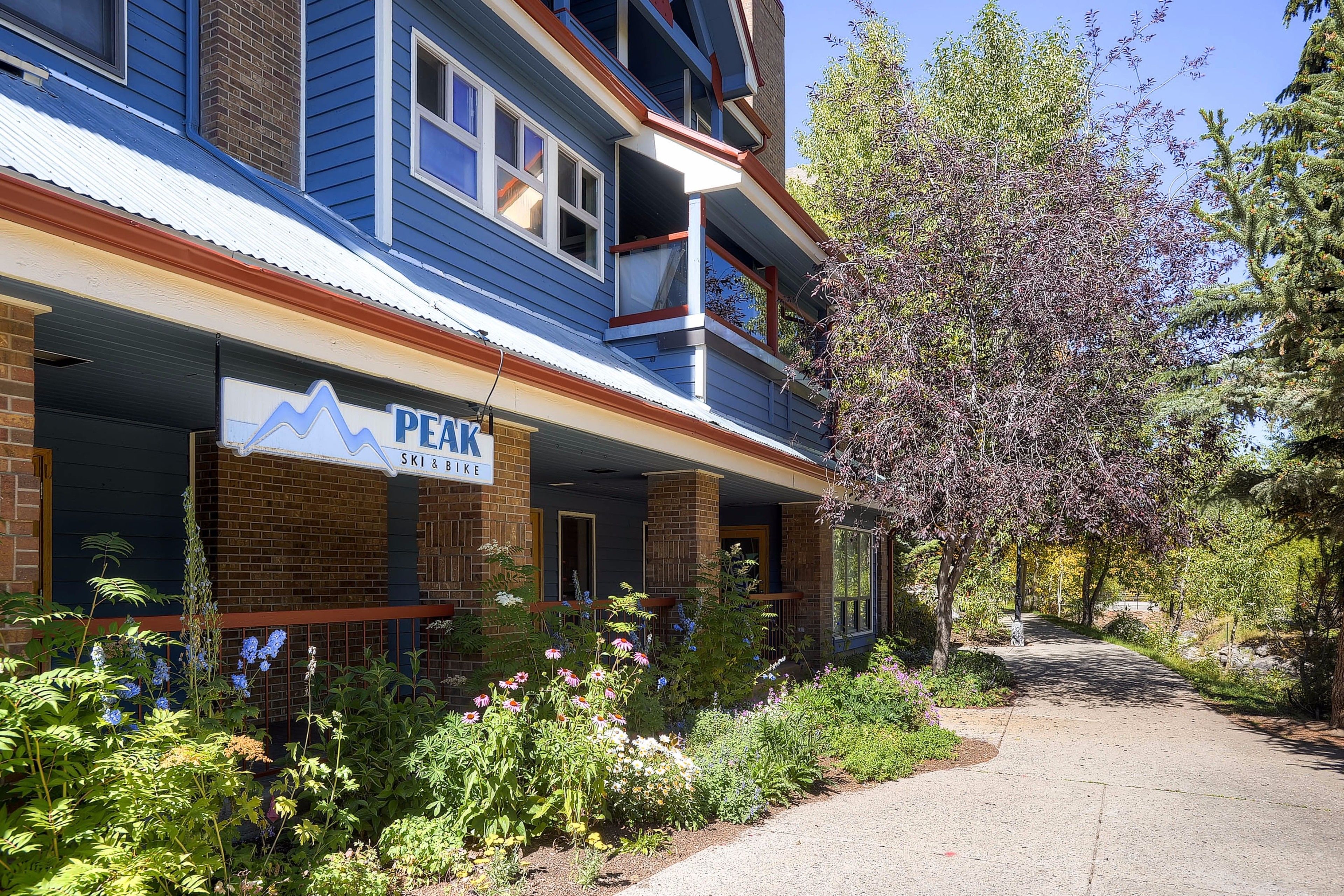 A building with a sign reading "PEAK Ski & Bike" and a covered porch with a brick facade.