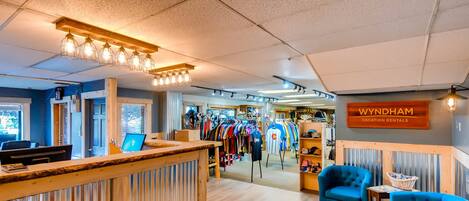 L’intérieur d’un magasin de vêtements, avec un comptoir d’accueil, des fauteuils bleus et un panneau indiquant « Wyndham Vacation Rentals ».