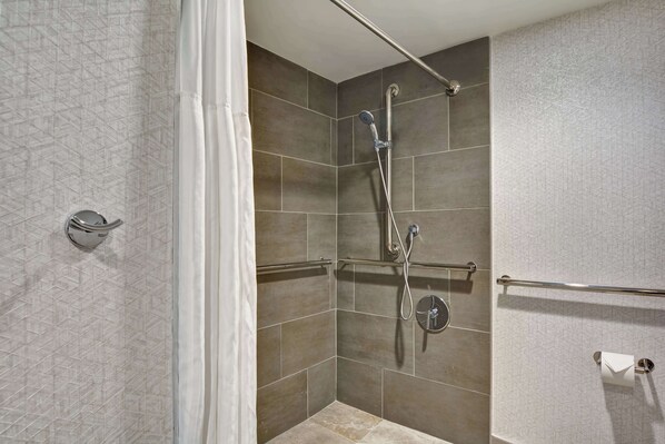 A shower area with a glass door, a handheld showerhead, a wall-mounted faucet, and a towel rack.