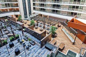 A multi-level atrium with open seating areas, a central staircase, and a pool.