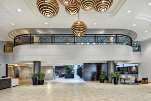 Welcome to our lobby, featuring a curved balcony, reception desk, and lush greenery.