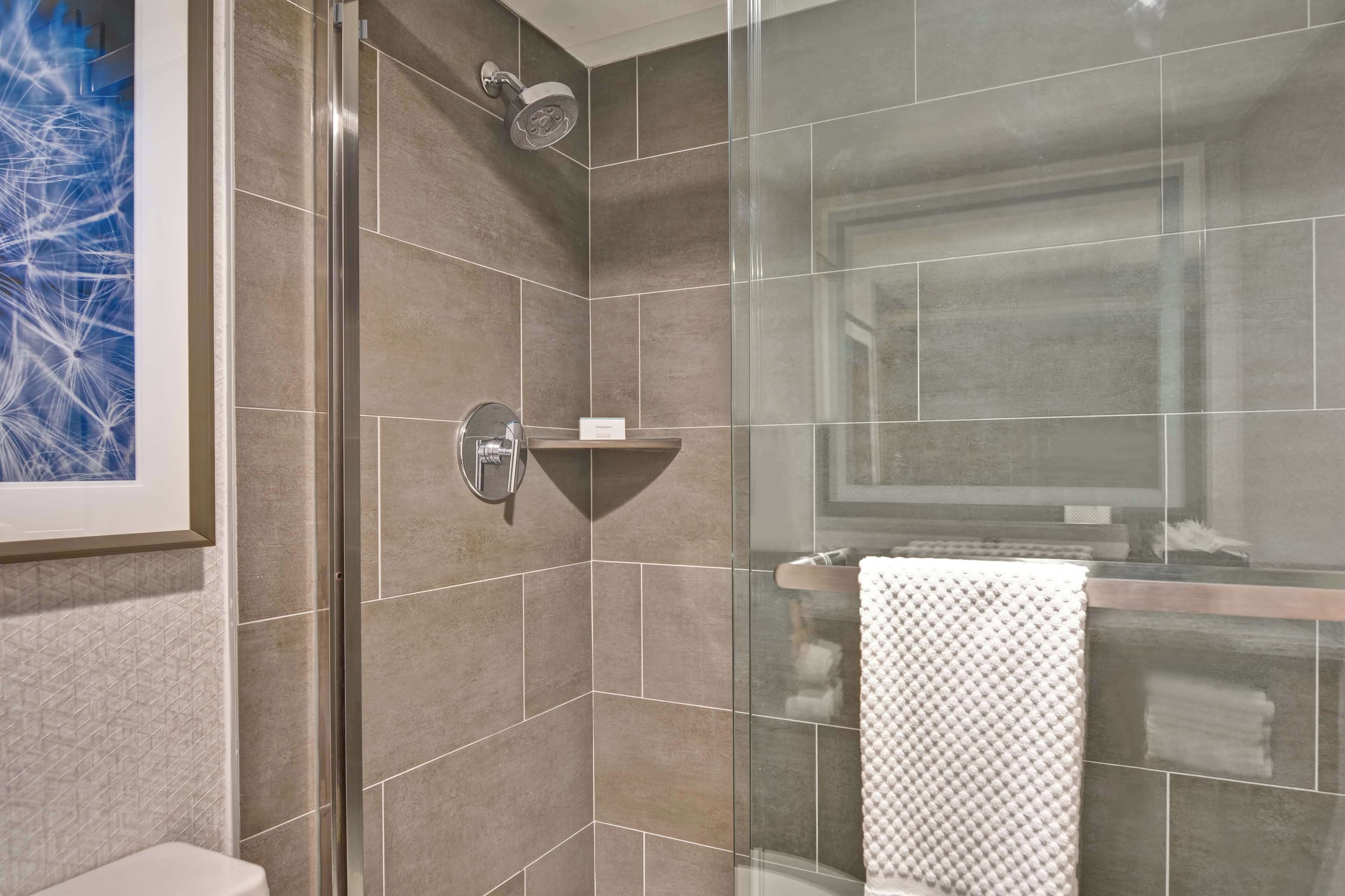 A modern bathroom with a glass shower enclosure, a white toilet, and a towel rack.