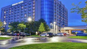 Un grand hôtel à plusieurs étages, doté d’une façade incurvée, de nombreux balcons et d’un parking où sont stationnés divers véhicules.