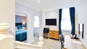 A hotel room with a bed, a desk, a chair, a TV, and a window with curtains. - Aston Court Derby City Centre by Belvilla (Derby)