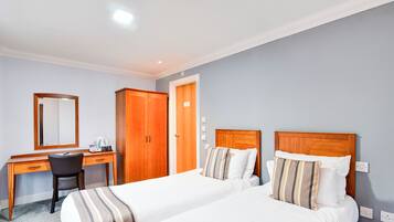 Une chambre d’hôtel avec deux lits, un bureau, une chaise et une armoire.
