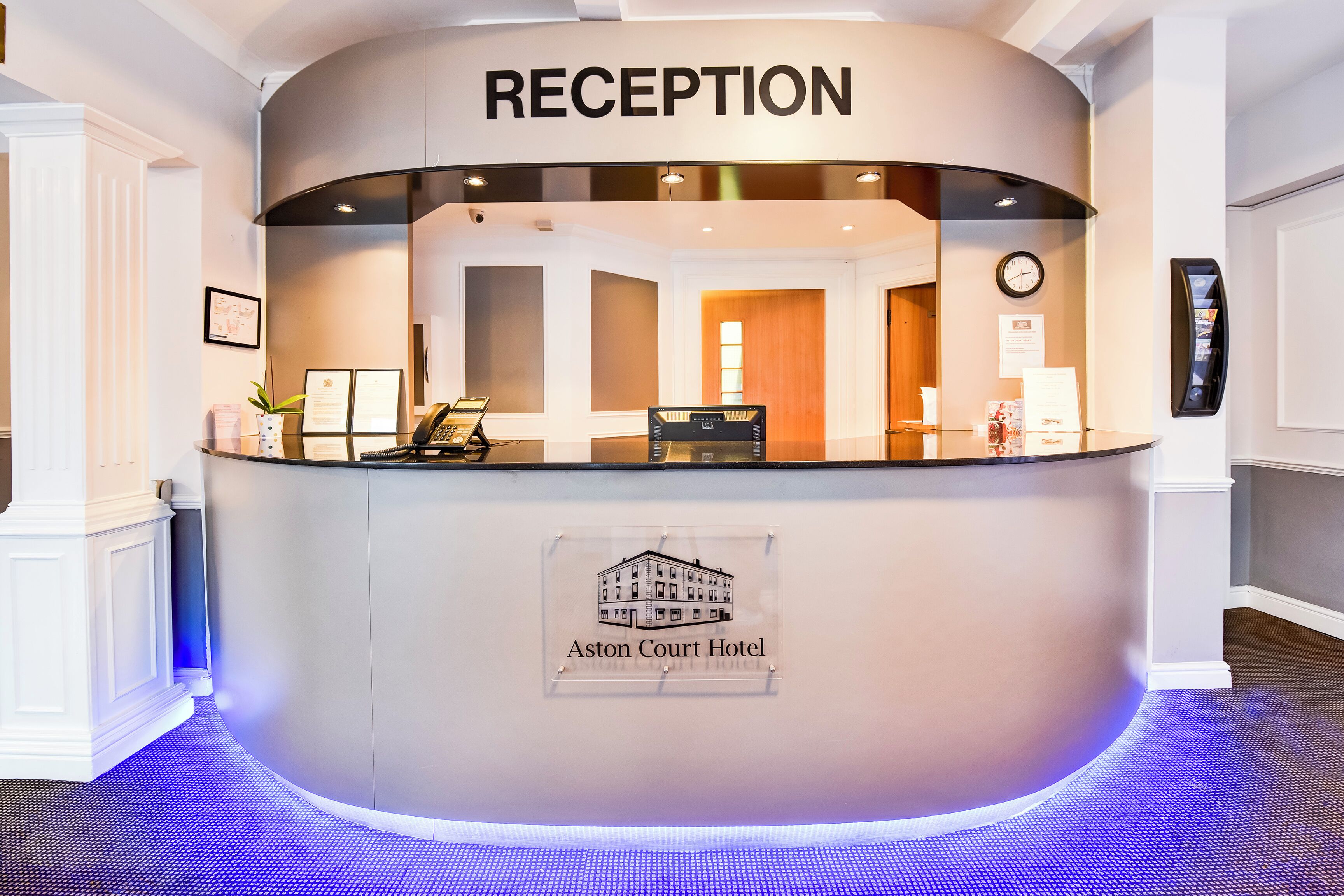 A reception desk at Aston Court Hotel with a sign indicating the reception area.