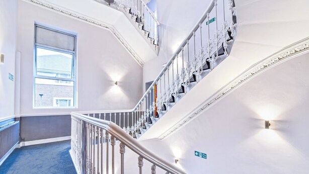 A multi-level interior with a staircase, a large window, and directional signs. - Aston Court Derby City Centre by Belvilla (Derby)