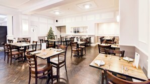 A spacious dining area with multiple tables and chairs, a Christmas tree, and a kitchen in the background. - Aston Court Derby City Centre by Belvilla (Derby)