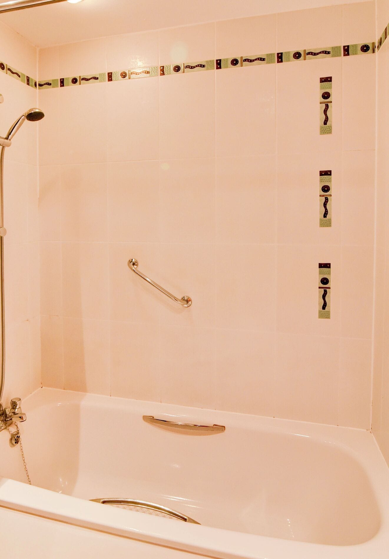 A bathroom with a bathtub, a shower, and a handrail.