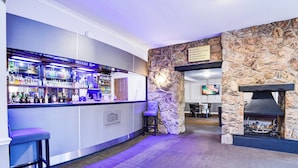 A bar area with a stone wall and a fireplace. There are bar stools and a television mounted on the wall. - Aston Court Derby City Centre by Belvilla (Derby)