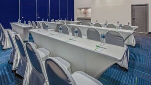 Ett konferensrum med långa bord, stolar och vattenflaskor.