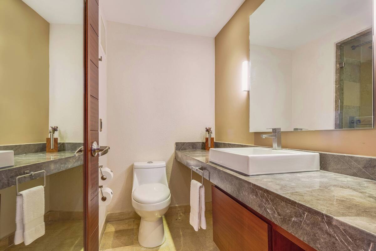A modern bathroom with a toilet, sink, and mirror.