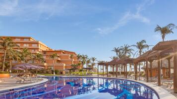Relax by the resort pool surrounded by lounge chairs, umbrellas, and palm trees.