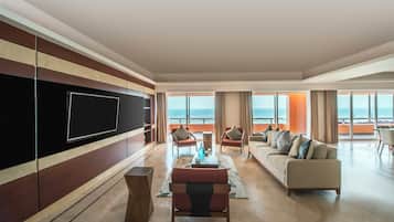 A spacious living room with a large flat-screen TV, a sofa, and chairs arranged around a coffee table.