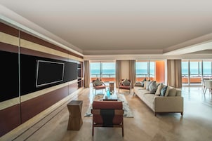 Amplia sala de estar con un televisor de pantalla plana grande, un sofá y sillones dispuestos alrededor de una mesa de centro.