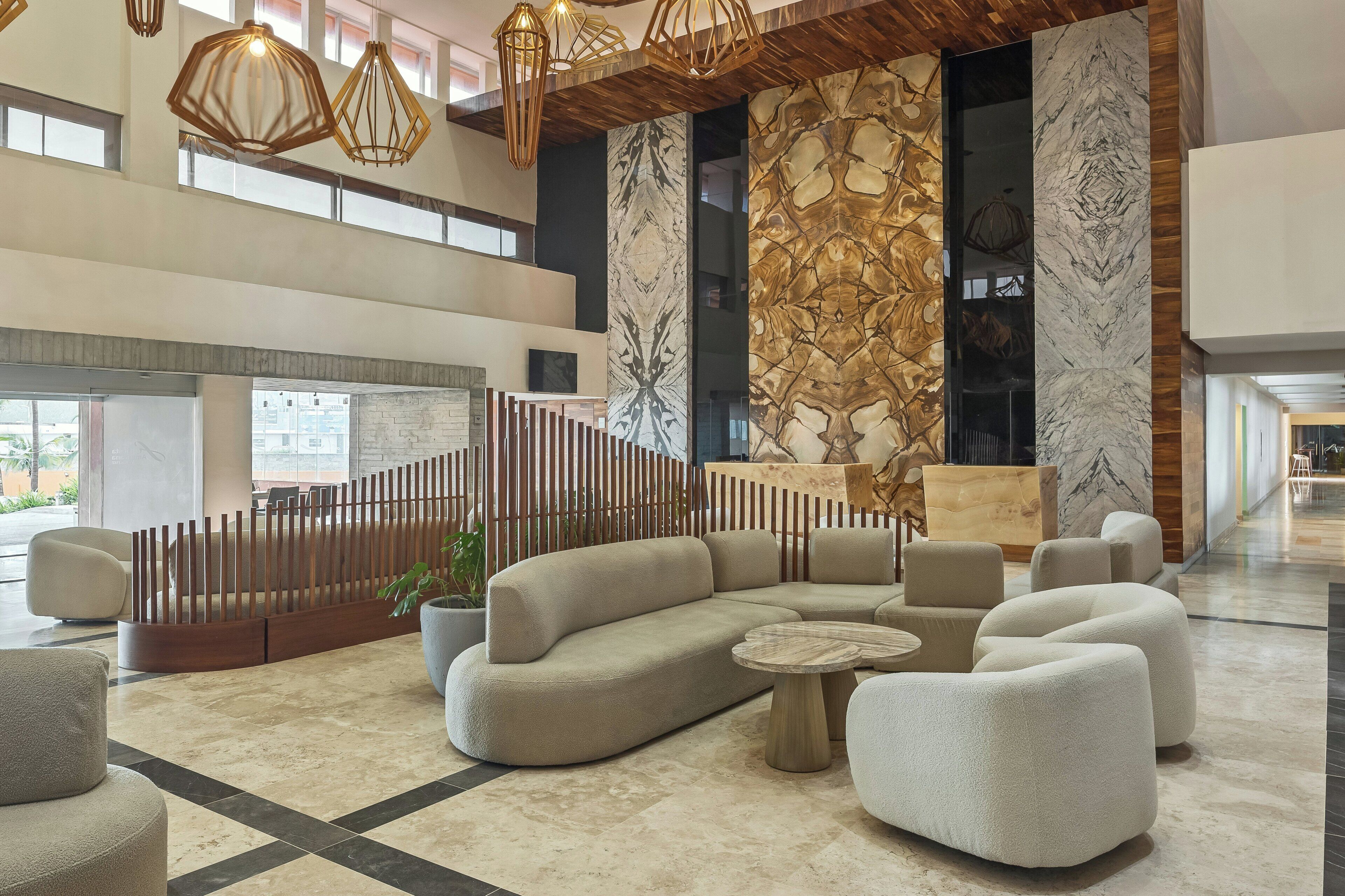 Un lobby amplio con un sofá modular moderno, una mesa de centro redonda y lámparas de diseño contemporáneo.