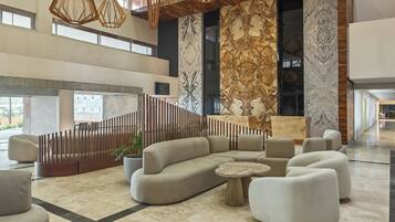 Un lobby amplio con un sofá modular moderno, una mesa de centro redonda y lámparas de diseño contemporáneo.