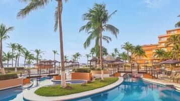 A resort pool area with palm trees, lounge chairs, and a building in the background.
