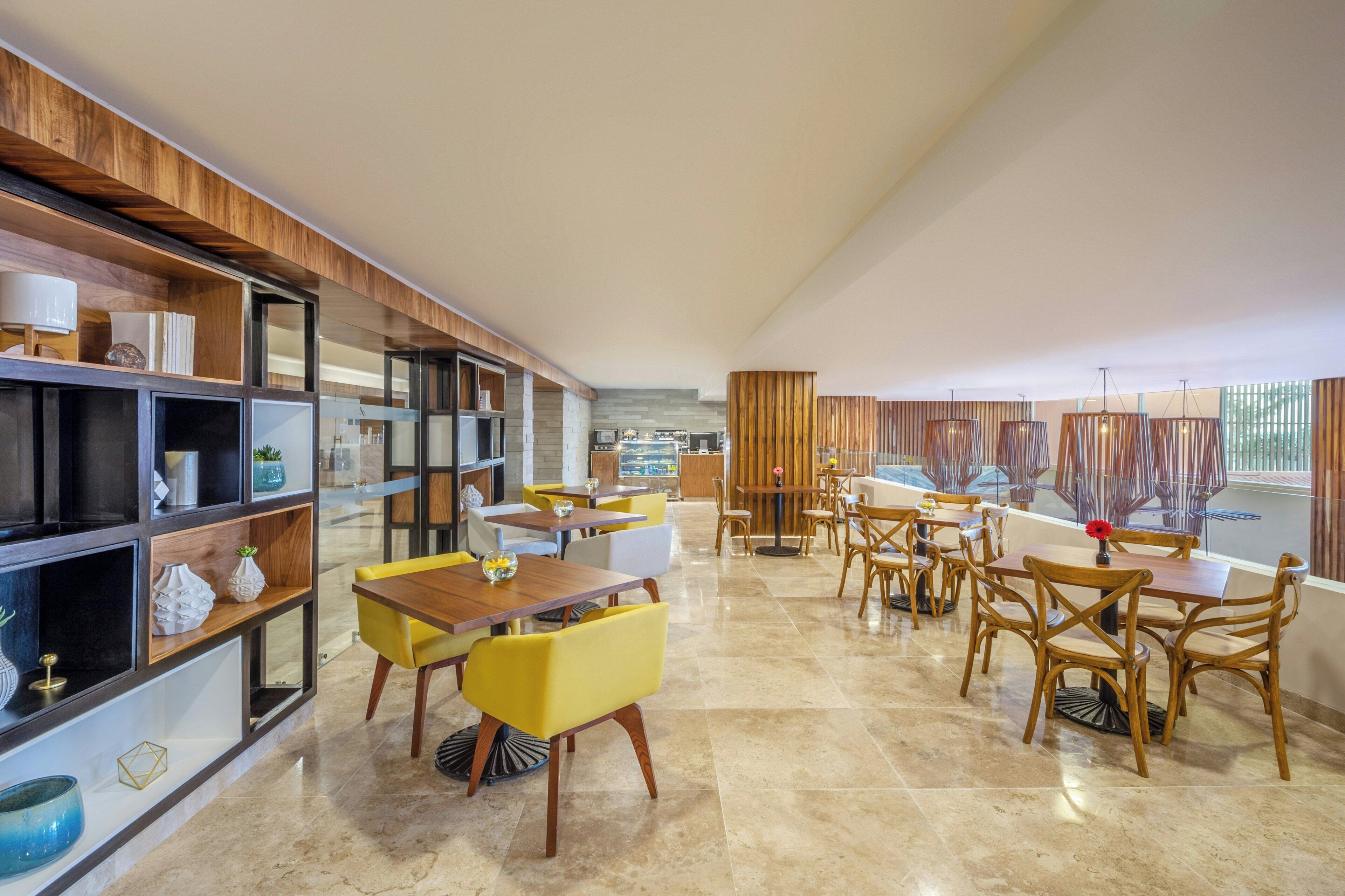 Uma sala de jantar moderna com prateleiras de madeira, cadeiras amarelas e vista para a cidade.