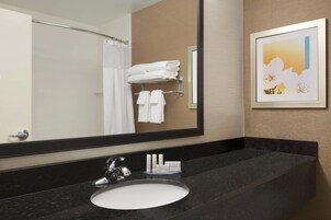 A hotel bathroom with a black granite sink, a large mirror, and a towel rack with folded towels.