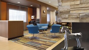 A hotel lobby with a reception desk, blue seating area, a clock, and a stone wall. - Fairfield Inn & Suites Colorado Springs Air Force Academy (Colorado Springs)