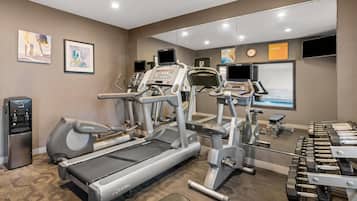 Un gimnasio con cintas de correr, elípticas y mancuernas.