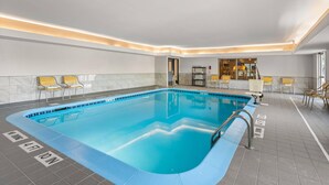 Una piscina con una marca de profundidad de 1 metro 47 centímetros, rodeada de sillas y una zona de recepción.