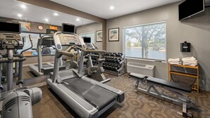 Un gimnasio con cintas de correr, mancuernas y equipo de ejercicio.