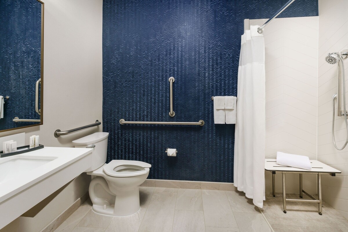 Un bagno con il water bianco, un lavabo, zona doccia e una maniglia.