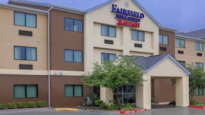 Un hotel Fairfield Inn & Suites Marriott de diseño moderno, con entrada cubierta y un área ajardinada con pequeños árboles.