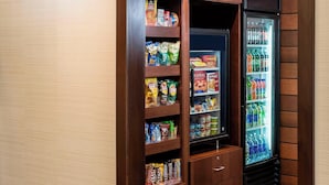 Un mercado de barrio con armarios de madera, una vitrina refrigerada y estantes llenos de aperitivos.