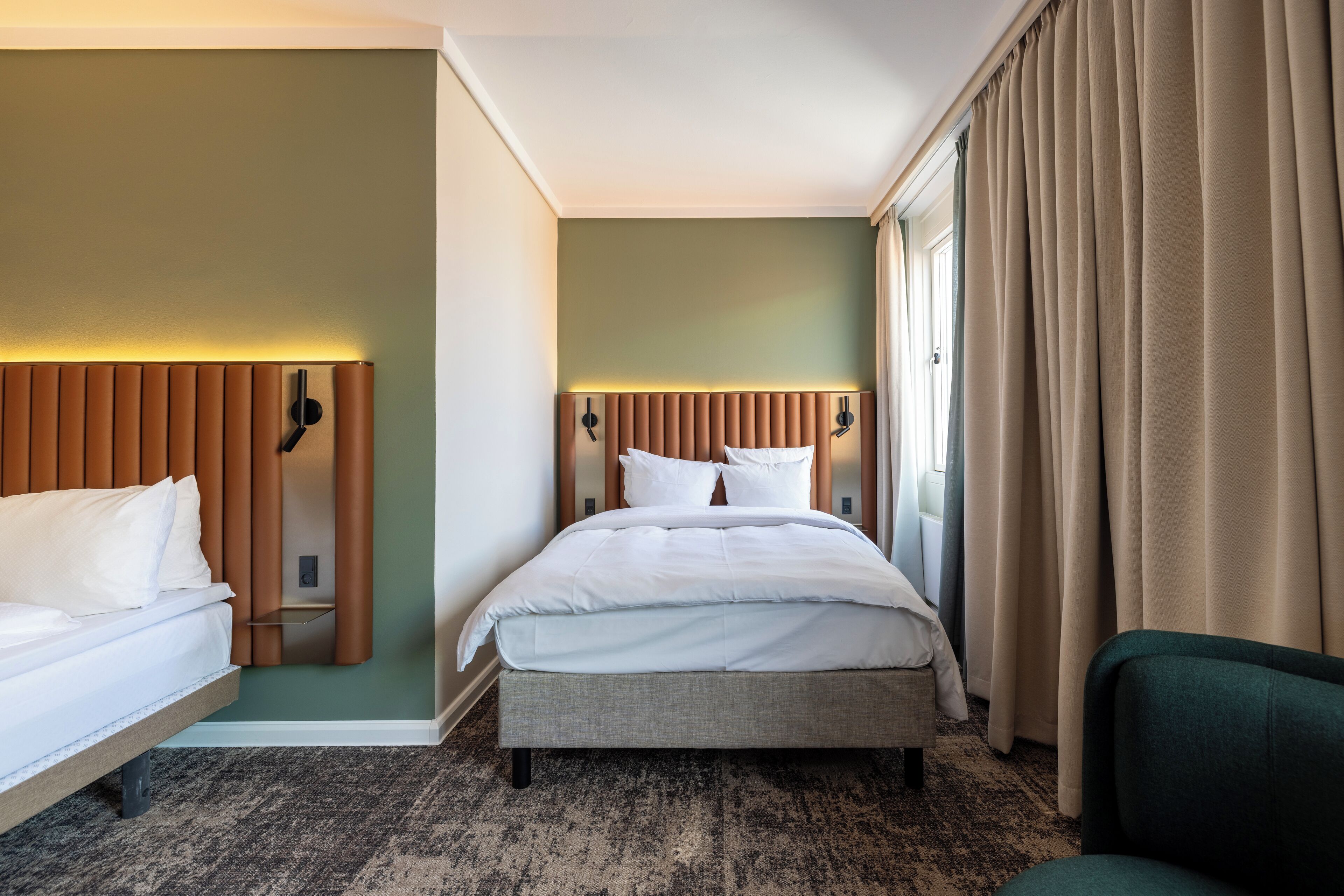 A hotel room with a bed, a bedside table, a lamp, and a chair.