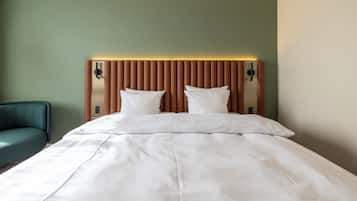 A neatly made bed with a wooden headboard and two bedside tables with lamps.