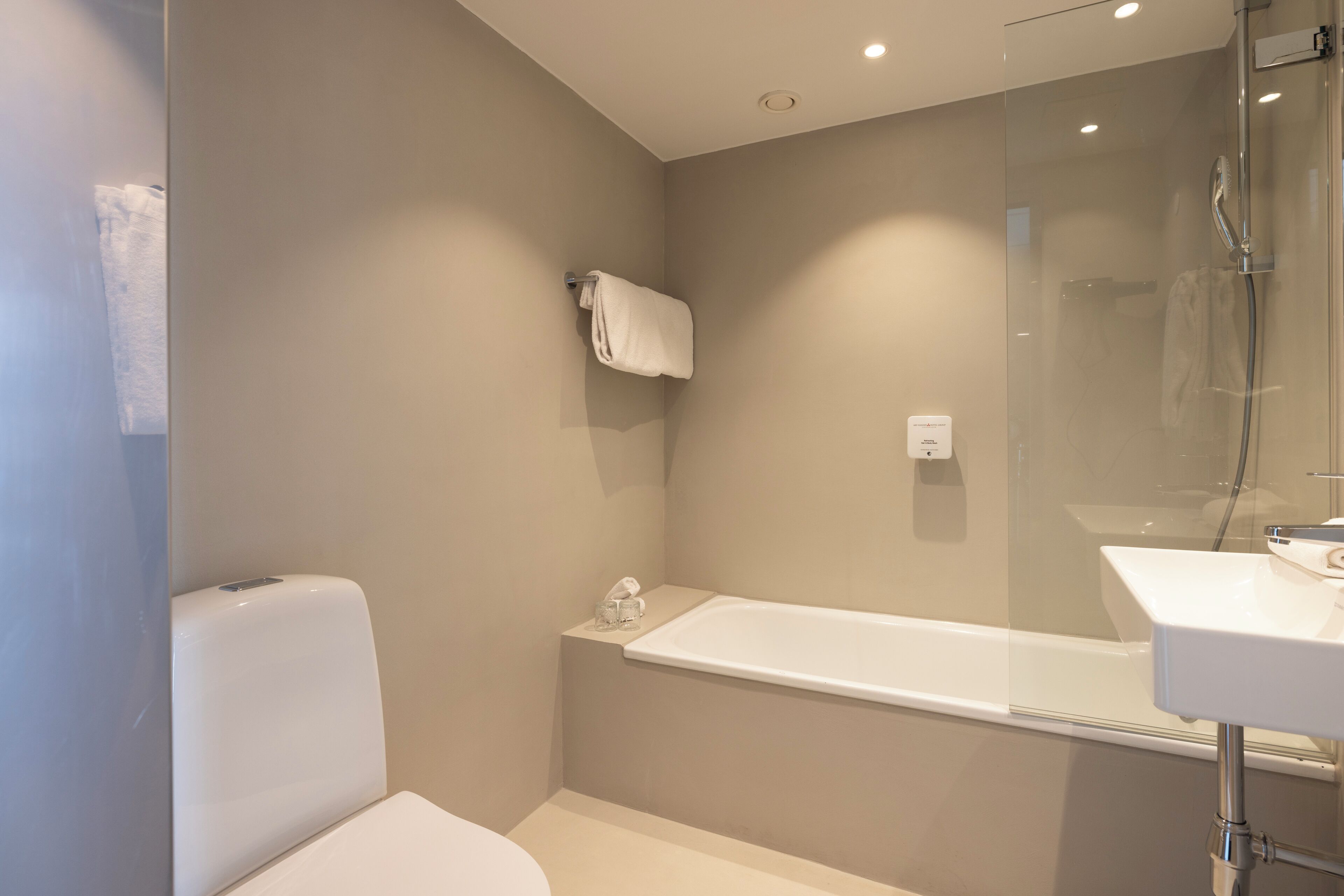 A modern bathroom with a glass-enclosed shower, a white toilet, and a white sink.