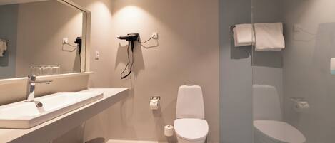 Ein modernes Badezimmer mit großem Spiegel, Waschbecken, Toilette und Duschbereich.