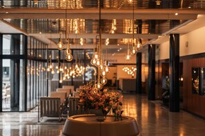 A modern interior with hanging light fixtures and a central floral arrangement. - Imperial Hotel (Copenhagen)