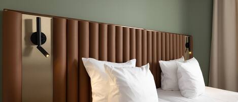 Una habitación de hotel con una cama grande, cabecera con listones verticales y una lámpara de pared.