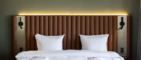 A hotel room with a large bed, a padded headboard, and two bedside tables with lamps.